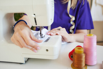 Obraz na płótnie Canvas a woman sews on a sewing machine