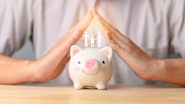Businessman take a position to protect on the piggy bank and family in hand, donation, saving, charity, family finance plan concept, fundraising, superannuation, financial crisis concept