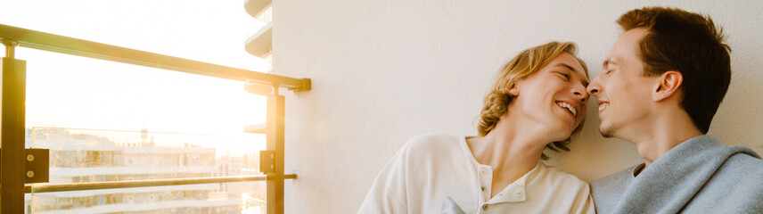 European gay couple hugging while resting together on balcony