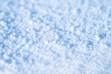 Obraz premium Snow with melted ice crystals and soft blue shadows on a sunny winter day. Background. Selective focus