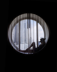 Silhouette of woman wearing hat sitting in the round window