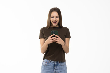 Fototapeta premium Photo of a shocked positive emotional surprised young woman posing over white wall background using mobile phone.
