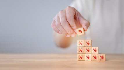 nterest rate financial and mortgage rates concept. Hand putting wood cube block increasing on top with icon percentage symbol upward direction