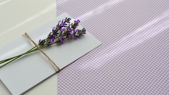 Mockup of  paper  blank white card with lavender flowers on lilac and white background close-up. Happy Birthday, Valentine's day, wedding, Mother's Day invitation greeting card concept.