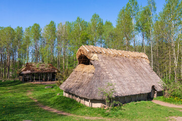 Fototapeta na wymiar Longhouse and hut on a meadow in a beautiful landscape at springtime