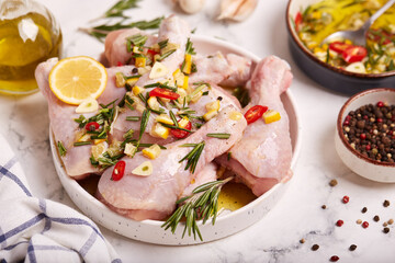 Raw Chicken legs marinated with olive oil, lemon, rosemary, hot pepper and garlic. Ready to cook. Recipe for healthy homemade food. 