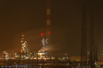Fototapeta na wymiar An oil and gas processing plant. Technological installation at an oil refinery. Lighting of factory equipment at night. The light from the lamps at the enterprise