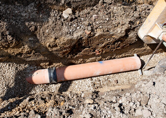 Ground workers installing new clay drainage pipe during deep drainage works on new residential housing development construction site