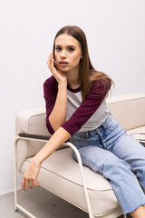 Obraz premium Young pretty woman sitting on her white sofa