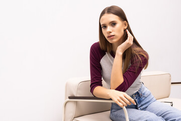 Obraz premium Young pretty woman sitting on her white sofa