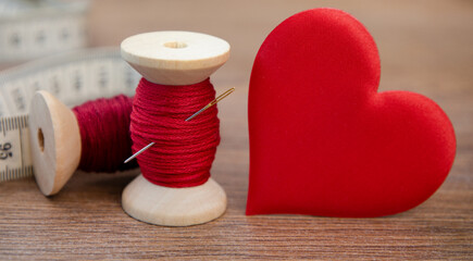 A spool of red thread and a heart.Sewing accessories.The concept of decor, needlework, love