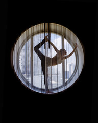 Silhouette of woman doing yoga in the round window