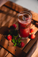 Summer red drink coctail in glass jar, with fresh berries on wooden table