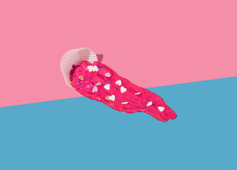 Magenta paint spilled out of a pastry cup with hearts on a light blue background. Romantic love...