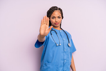 black afro woman looking serious showing open palm making stop gesture. nurse concept