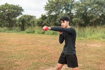 A young man throws a quick left jab. Weighted shadow boxing with a pair of dumbbells at an outdoor...