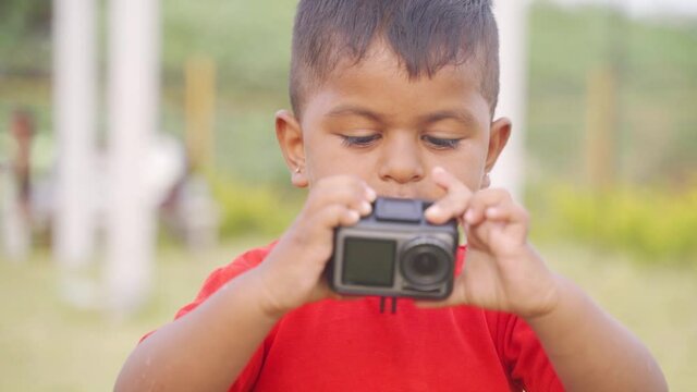 Close up shot of a little cute boy try to capture photos on camera - Concept of childhood playful lifestyle and future photographer.
