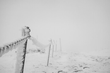 Chain fencing covered with ice and snow on a dangerous section of the trail in the mountains.