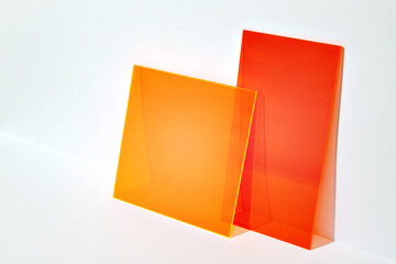 Red and orange acrylic shapes on a bright lit white background. Colourful minimalist stage for advertising, promoting, exhibition new products. Stylish abstract backdrop with space for text.  - obrazy, fototapety, plakaty