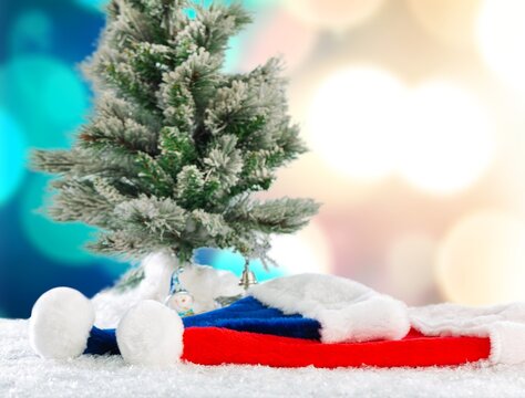 Santa Claus hat on snow with christmas tree