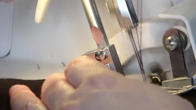 Close-up of the sewing foot and needle of a sewing machine sewing a garment.
