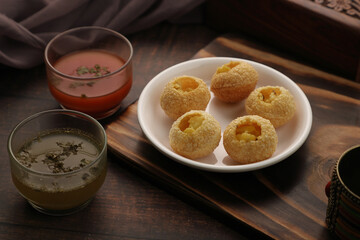 Indian Food Snacks Gol Gappe or Pani Puri or Puchka Water Balls in a White Plate with Flavoured Water - obrazy, fototapety, plakaty