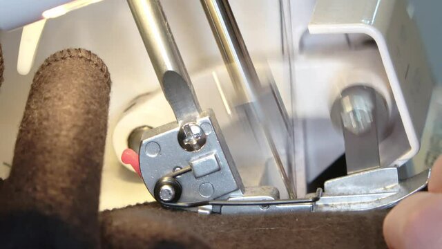 Close-up of the sewing foot and needle of a sewing machine sewing a garment.