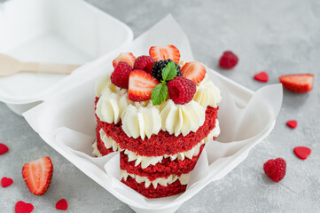 Red velvet bento cake. A small cake in a lunchbox on a gray concrete background. Valentine's Day Cake. Asian food trend. Cute gift for any holiday. Copy space.