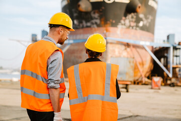 Multiracial man and woman talking while working at port