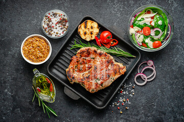 Food background. Dinner of grilled pork steak with spices and fresh salad. Top view, flat lay