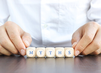 hand hold Wooden cube with the text. myths on the wooden table.