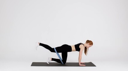 Young Sporty Woman Using Resistance Loop Band For Glute Training In Studio