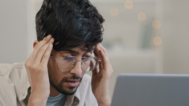 Close-up arab business man student male bearded boss leader with glasses guy works with laptop problems suffers from headache massages head feeling stress solves difficult trouble searching solution