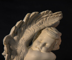 Close up of a white angel on a dark background. Moment of grief at the end of a life. Last farewell. Funeral concept.