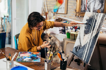 man enjoying time with his dog while painting a picture at home