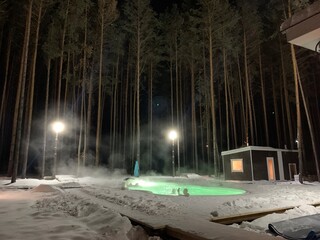 heated pool with steam with people in winter in a pine forest