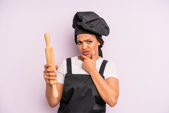 afro black woman with mouth and eyes wide open and hand on chin. chef with a roller pin