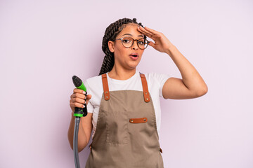 afro black woman looking happy, astonished and surprised. gardener hose concept