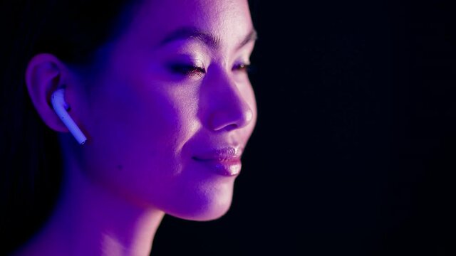 Beautiful Asian Lady Wearing Wireless Airpods Listening Music Illuminated By Neon Light