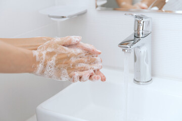 Washing hands under the flowing water tap. Washing hands rubbing with soap for corona virus prevention, hygiene to stop spreading corona virus in or public wash room. Hygiene concept hand detail