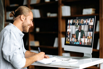 Smart modern Caucasian guy, student or freelancer, listens to an online webinar, lecture, notes...