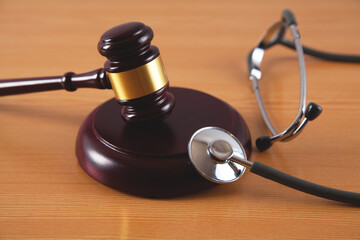 Medical stethoscope and judge gavel on an isolated wooden background.
