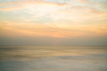 Beautiful long exposure seascape of smooth wavy sea and cloud. orange horizon with first sunrise sky.