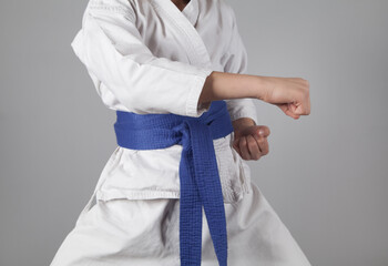 Young boy training karate on gray background. Boy with a kimono.