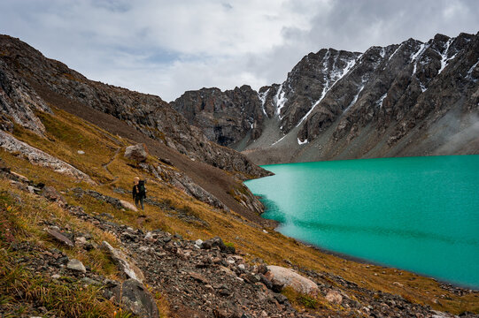 Male trekker backpacker hiking at bank of Beautiful landscape of turquoise Ala-Kul Lake, Karakol valley, Issyk-kul region, Ala-kul lake Terskey Alatau mountain range, Kyrgyzstan, Central Asia.