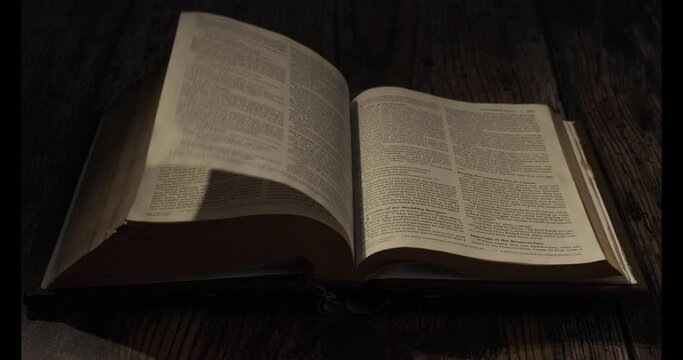 A  page in the bible is being turned over, contrast Night atmosphere
