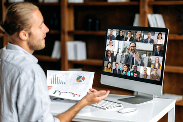 Fototapeta na wymiar Brainstorming, online business meeting. Side view of a corporate employee communicating with a group of multi-ethnic colleagues via video call, analyzing financial statements, planning strategy