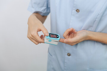 Pulse oximeter with hand of doctor isolated on white. The concept of portable digital device to measure person's oxygen saturation. Measuring oxygen saturation, pulse rate and oxygen levels.