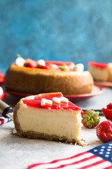 Cheesecake slice, New York style classical cheese cake with strawberry on blue background. Slice of tasty cake on white plate