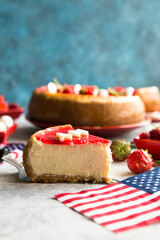 Cheesecake slice, New York style classical cheese cake with strawberry on blue background. Slice of tasty cake on white plate